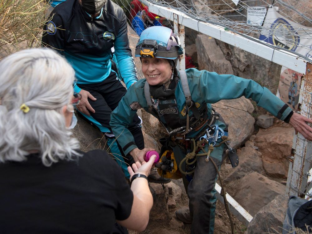 Woman wearing hardhat smiles and emerges from cave