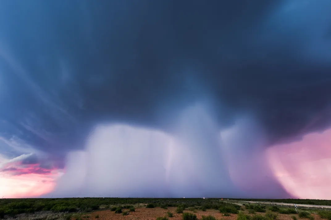 Storm clouds near Andrews dump wide columns of precipitation on the plain.
