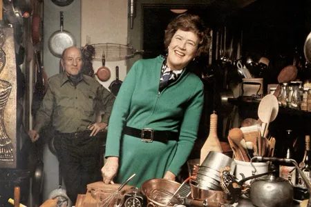 Julia Child in her kitchen with husband Paul behind her