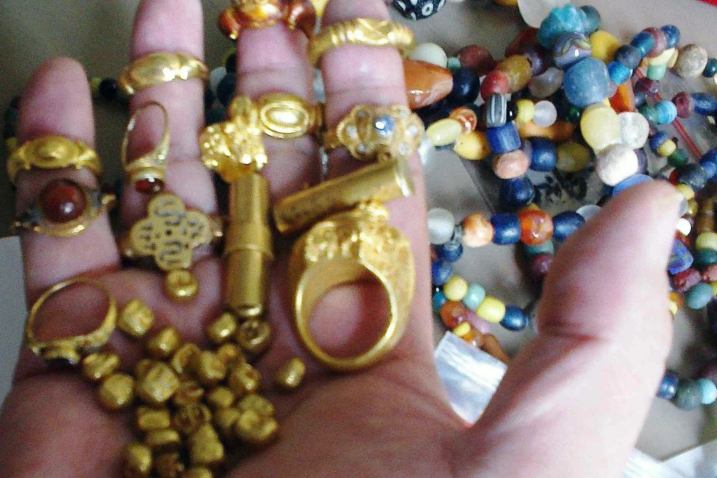 gold jewelry and beads held in a hand