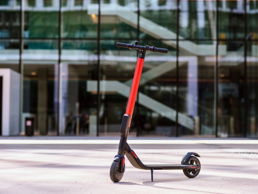 A for-rent electric scooter is photographed in front of a city building