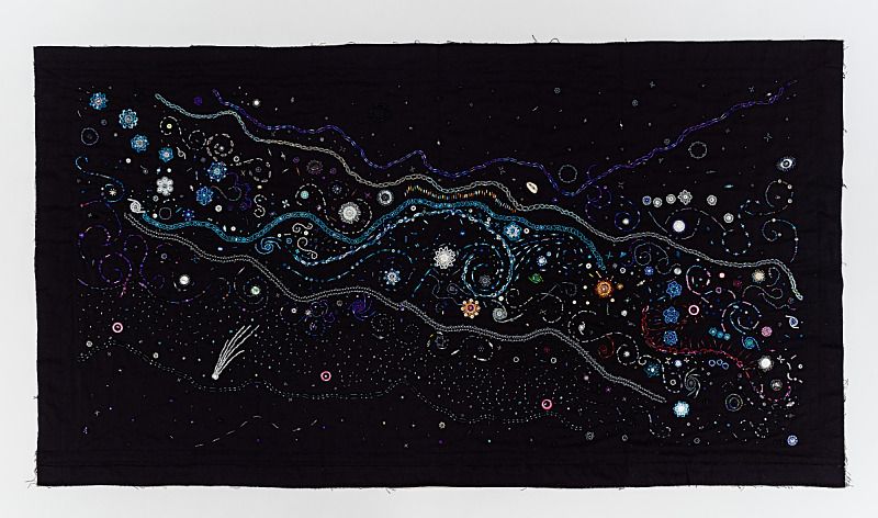 A textile artwork that uses colorful thread and beads to create a swirling, galaxy-like starscape.
