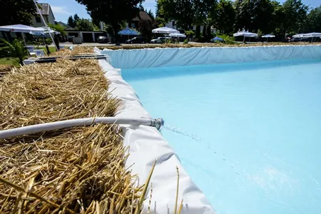 Water runs from a hose into a hay bale pool.