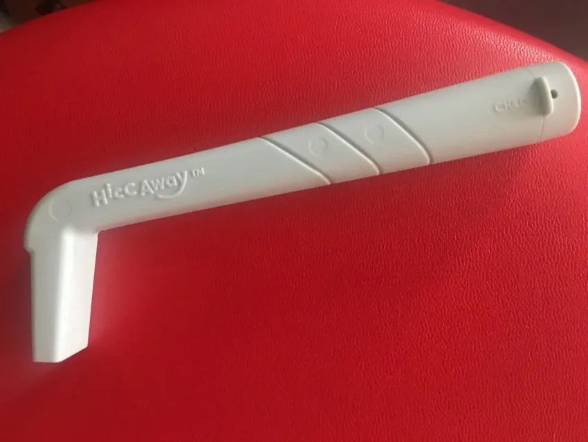 A blue L-shaped straw device sits on a red surface