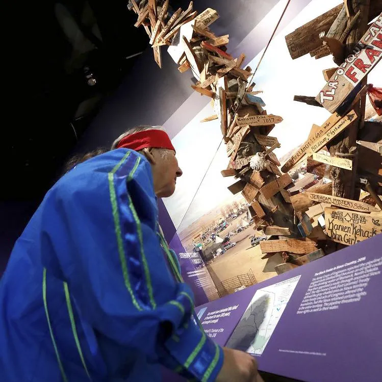 Elder from Onondaga looking at a mile marker post in a museum exhibit
