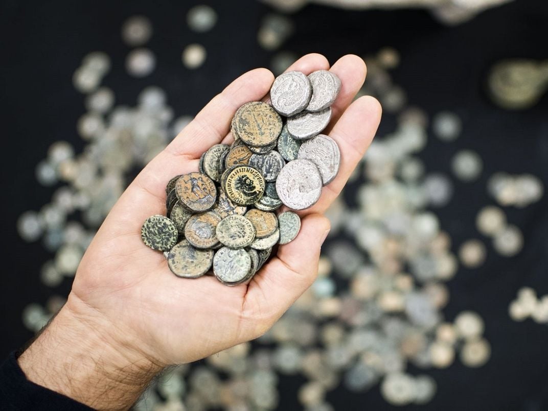 hand holding a lot of old coins