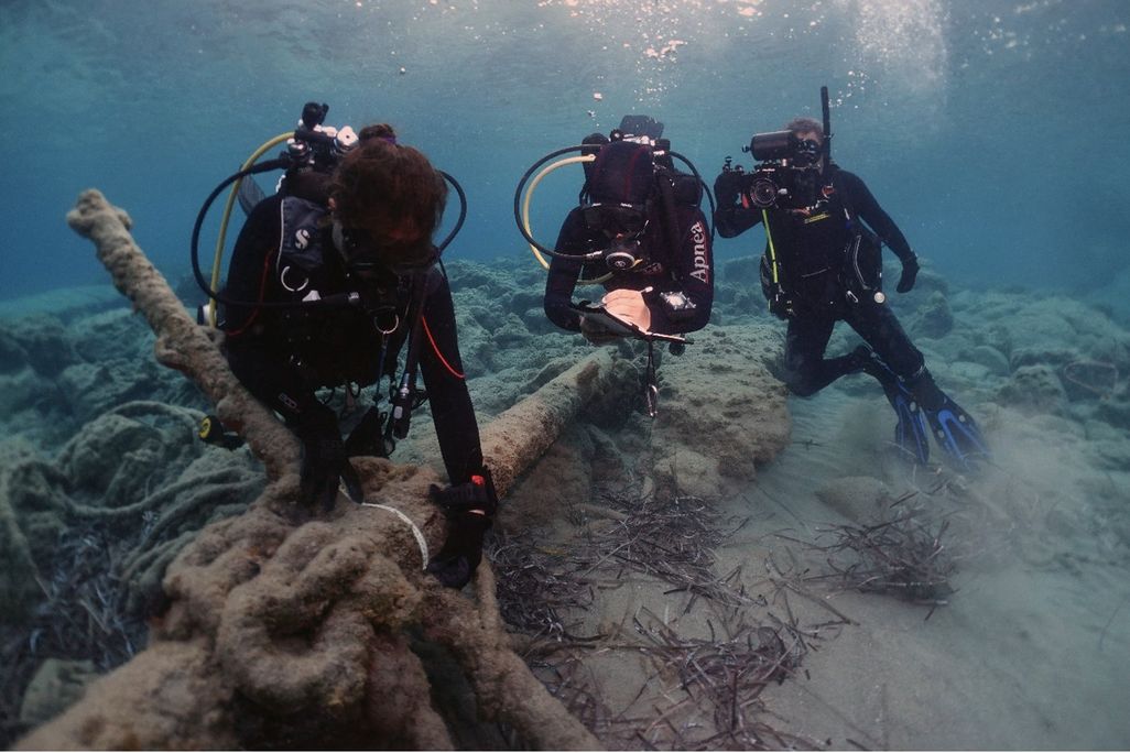 Underwater divers holding large anchor
