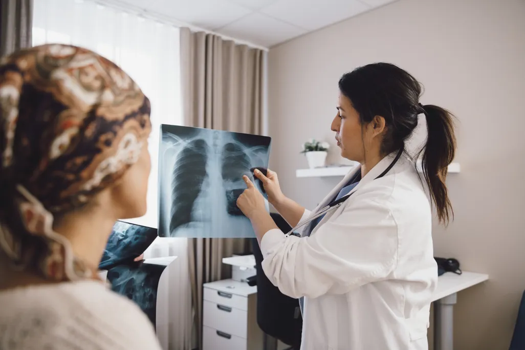 patient looking toward doctor pointing at an x-ray