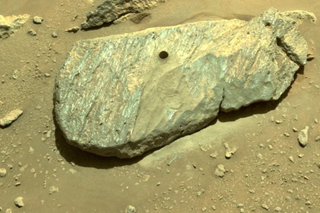 An image of a boulder with a hole drilled into it. The photo was taken by the Mars rover on Planet Mars and shows where the rover obtained its first rock sample from. 