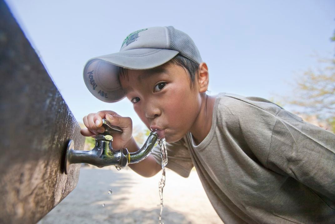 Image of child drinking from water faucet 