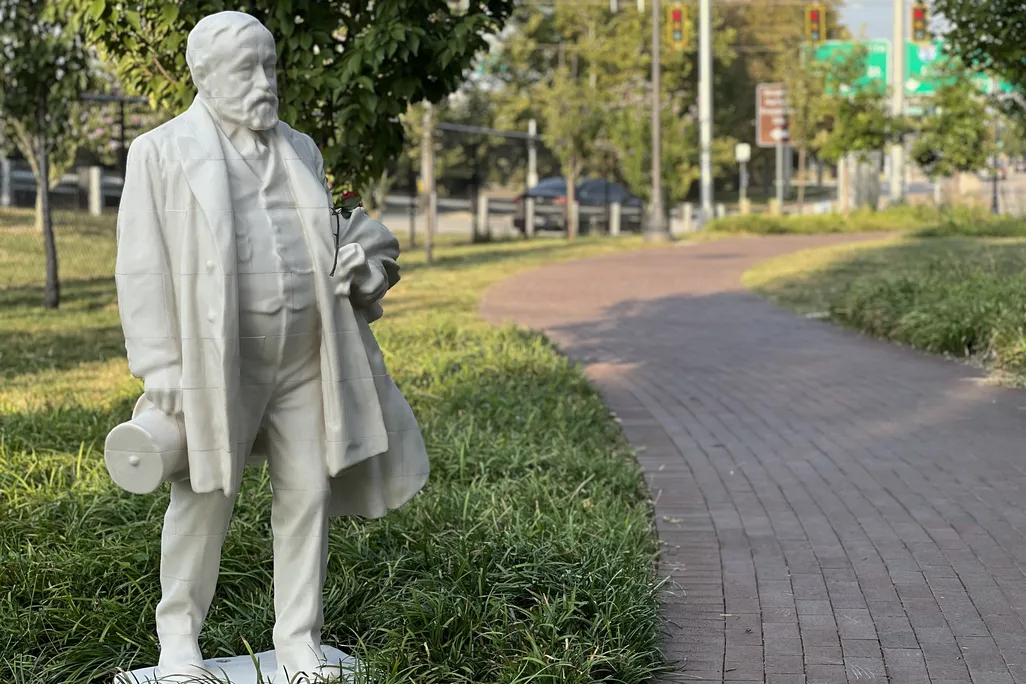 A statue of a bearded man next to a brick sidewalk