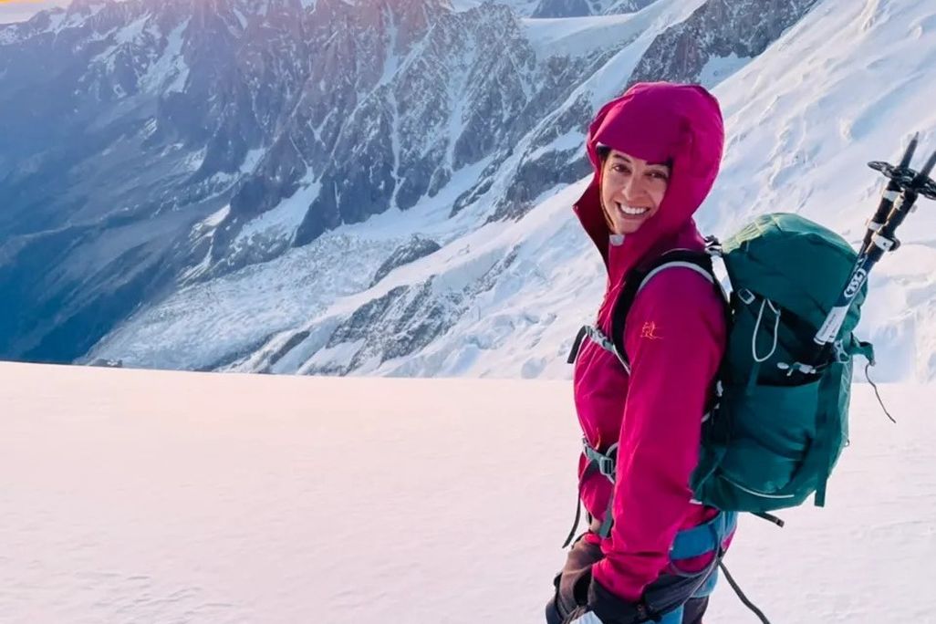 Preet smiles in front of mountains with a pack on her back