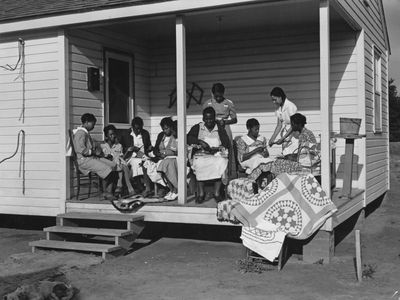 A group of women sewing a quilt on the porch of a property in Georgia, May 1939