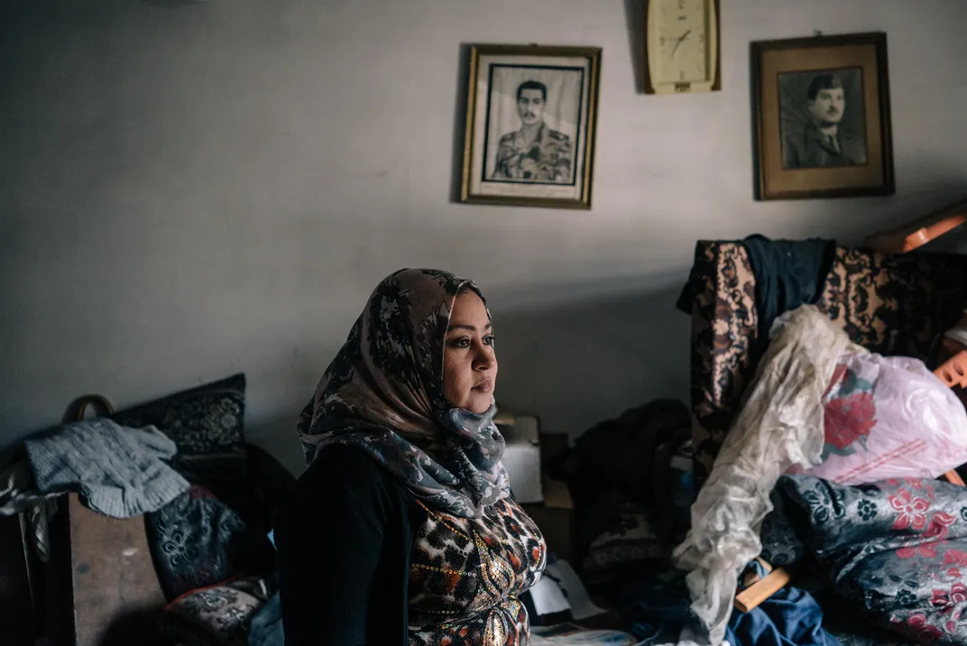 Salih visits her family home in Mosul, which had been occupied by ISIS militants. Above her are portraits of her late brother and father.