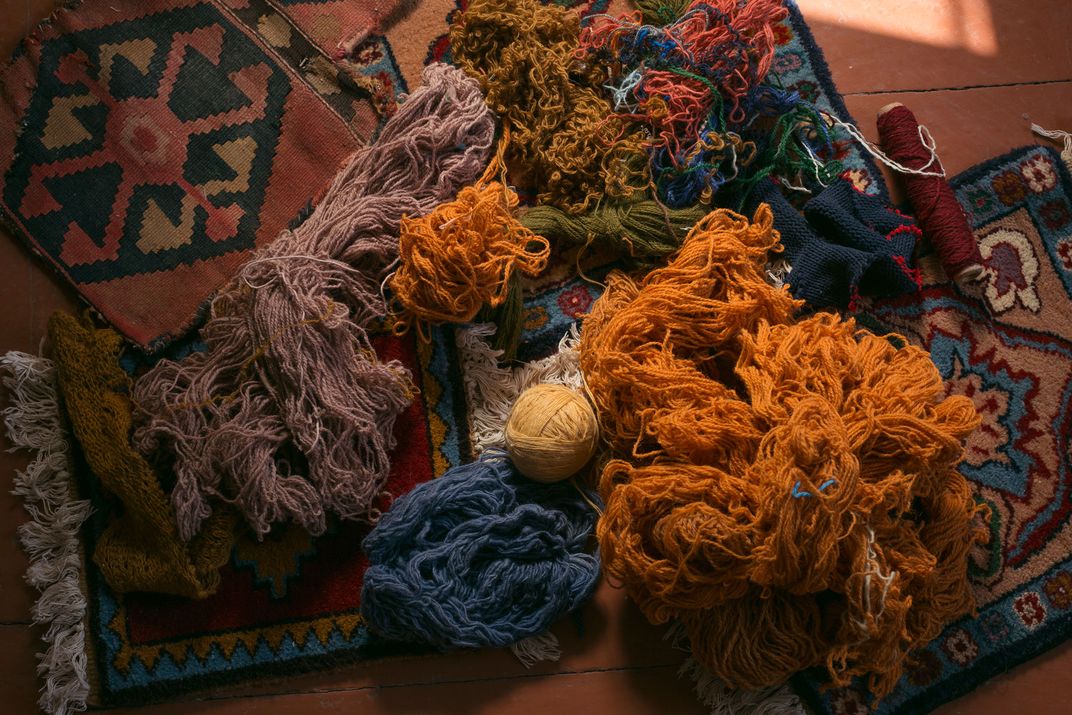 An arrangement of colorful yarn is placed carefully on top of a geometrically patterned rug.