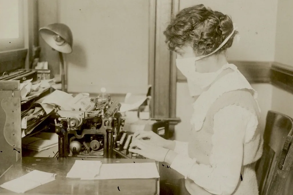 woman typing wearing a mask