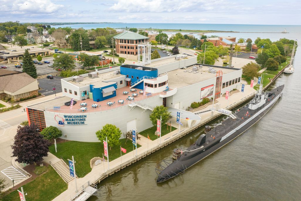 Submarine on river in front of large museum building