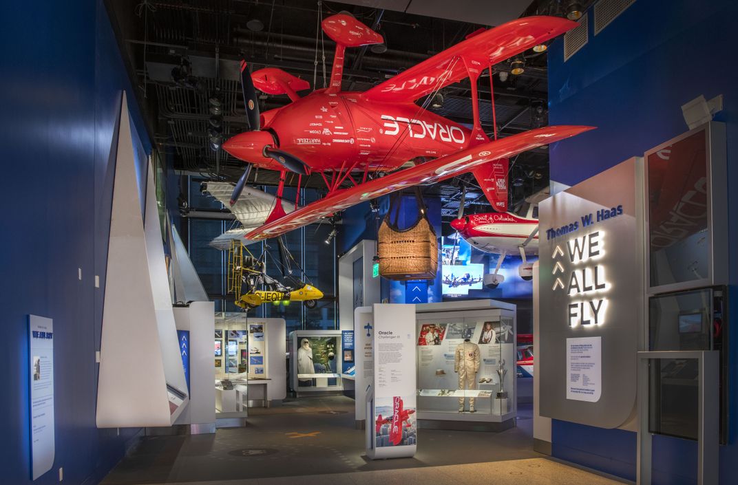 Bright red biplane hanging in the entrance of an exhibition.