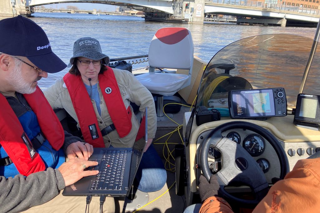 Researchers on a boat using a laptop