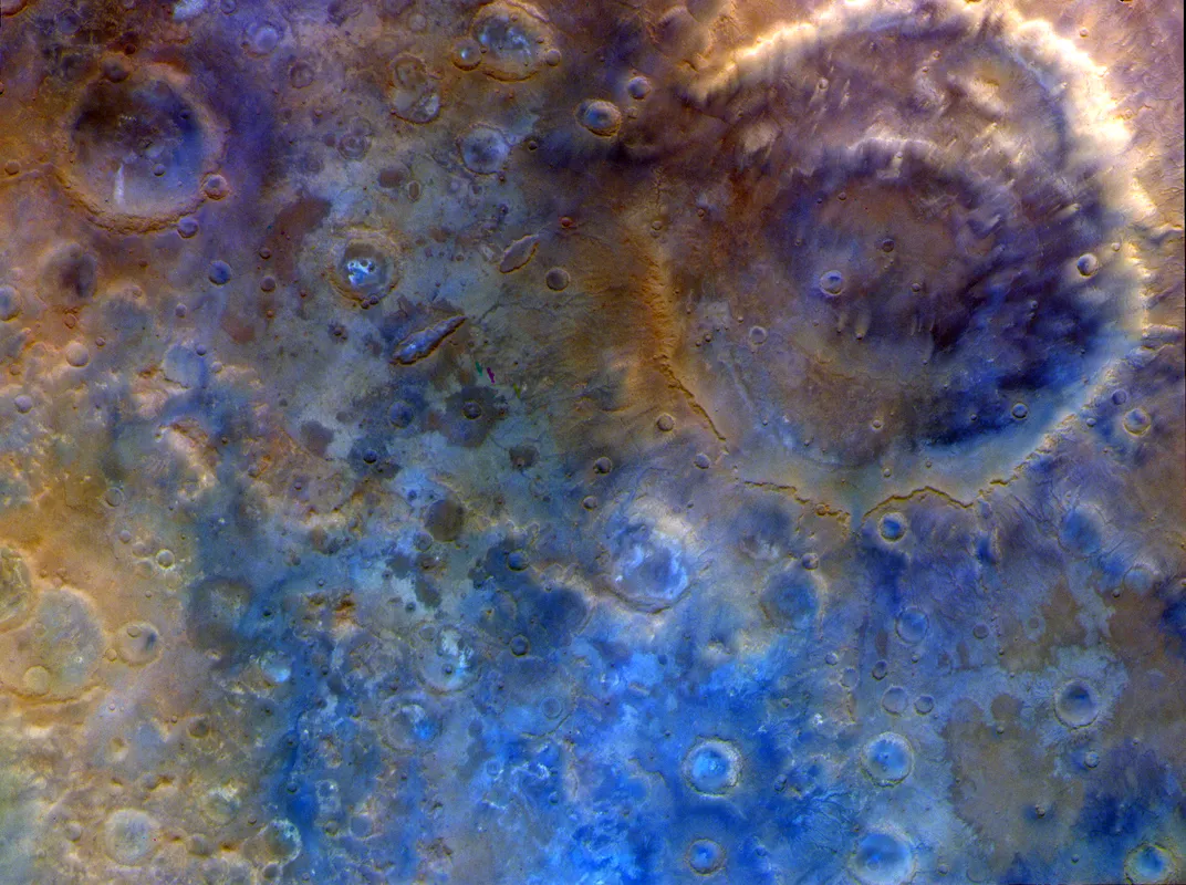 the cratered surface of Mars, seen with yellow, blue and purple hues