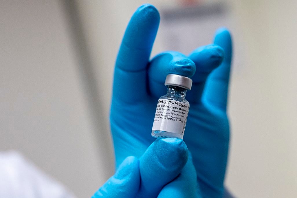 A gloved hand holds a generic Covid-19 vaccine