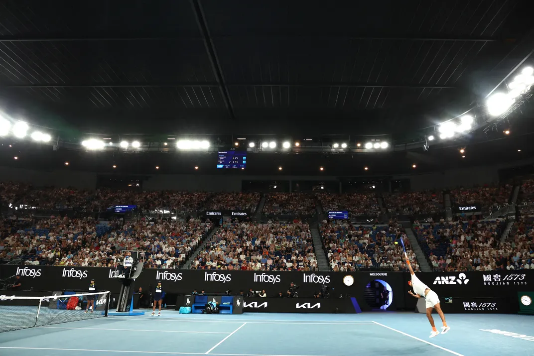 a dark tennis arena with the roof closed