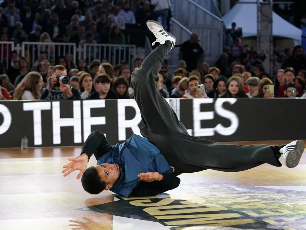 A man dancing on the ground in front of an audience