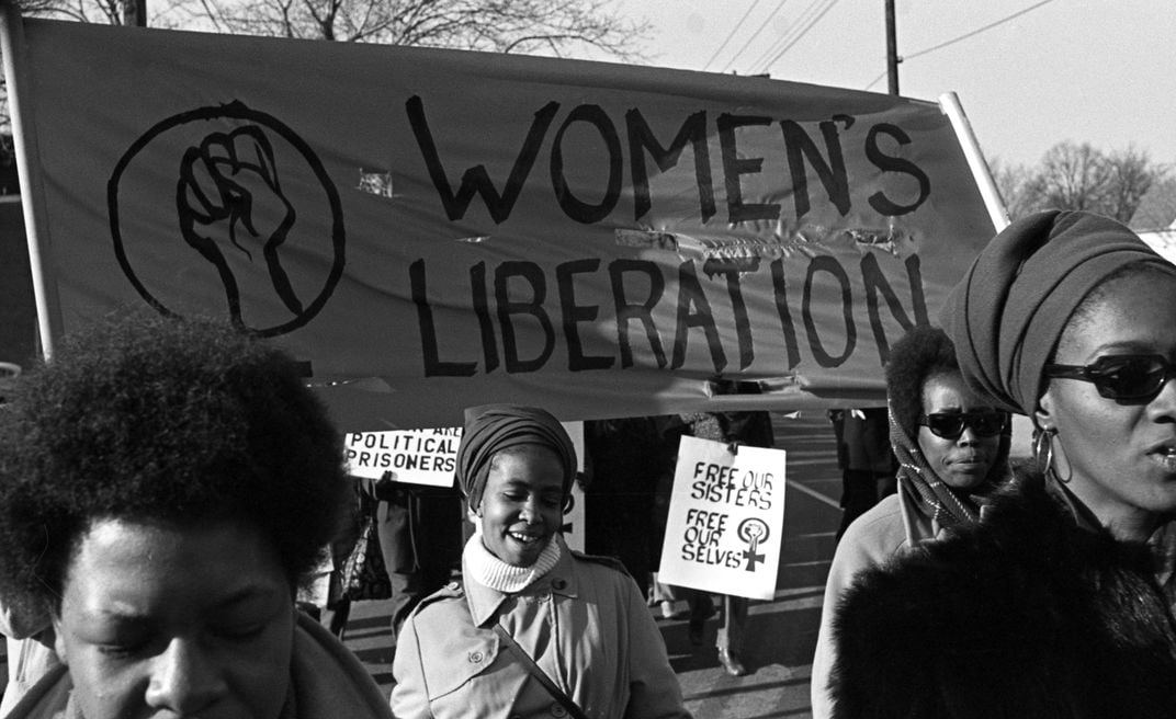 A group of women, under a 'Women's Liberation' banner, march in support of the Black Panther Party