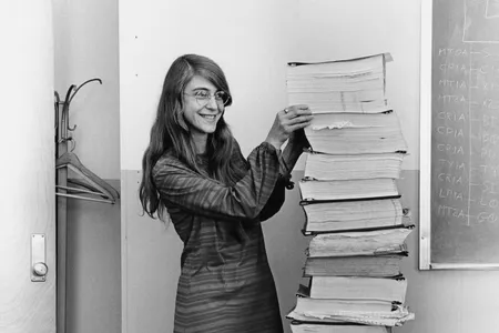 Margaret Hamilton stands next to a stack of program listings from the Apollo Guidance Computer in a photograph taken in 1969.