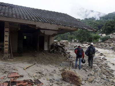 Residents walk near a destroyed house after a landslide in Teresopolis January 15, 2011.