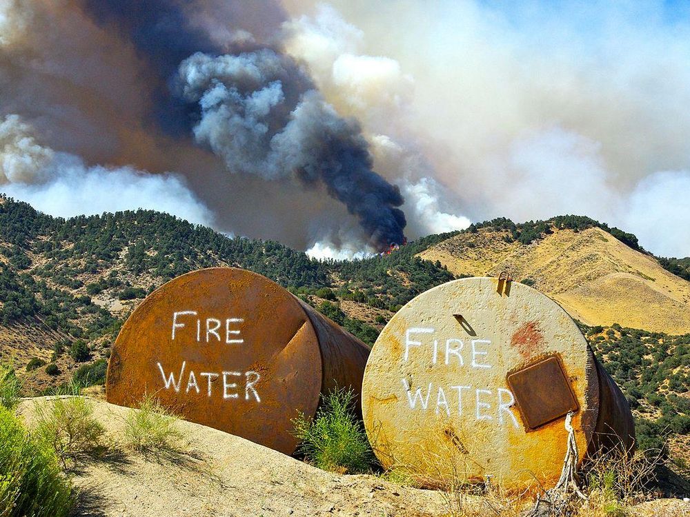 Tanks filled with water await possible use as a fire burns on the crest of a hill in Lebec, California, 2010