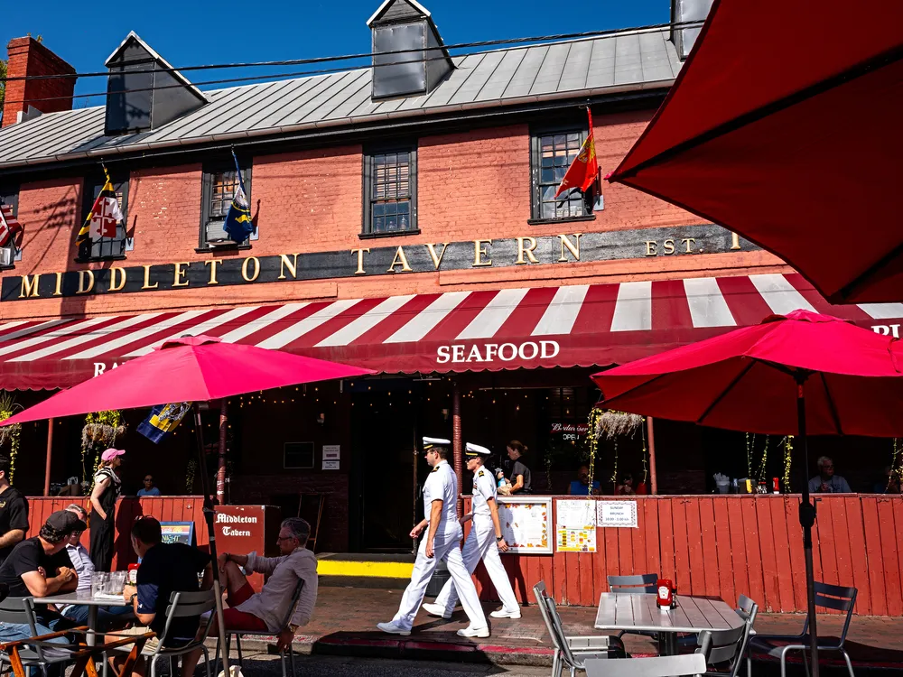 OPENER - Two U.S. Navy officers stroll past the sunlit Georgian splendor of Middleton Tavern in Annapolis, Maryland. Horatio Middleton established the tavern here in 1750. Today, visitors can order classic Chesapeake seafood, including oysters and rockfis