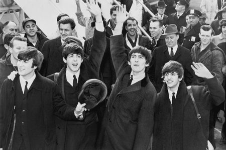 The Beatles step onto the tarmac at JFK Airport on February 7, 1964, arriving for their first performance in the U.S.