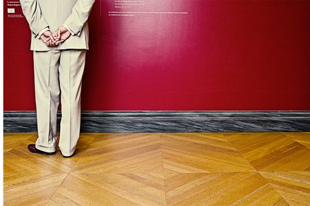 A man looks at artwork in the Louvre. 