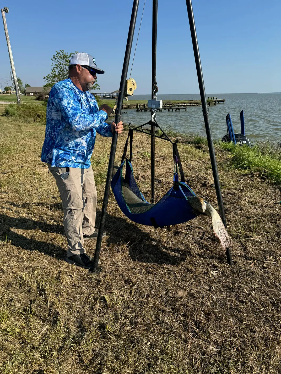 Man in blue jacket weighing a fish on a scale