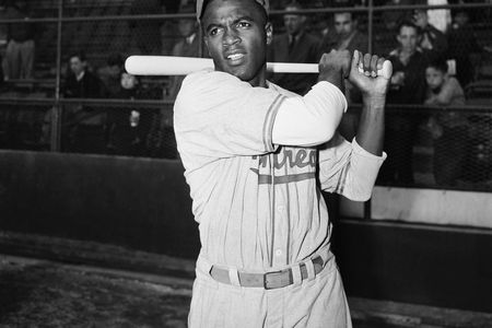 Jackie Robinson, is shown in post-swing position in front of the stands