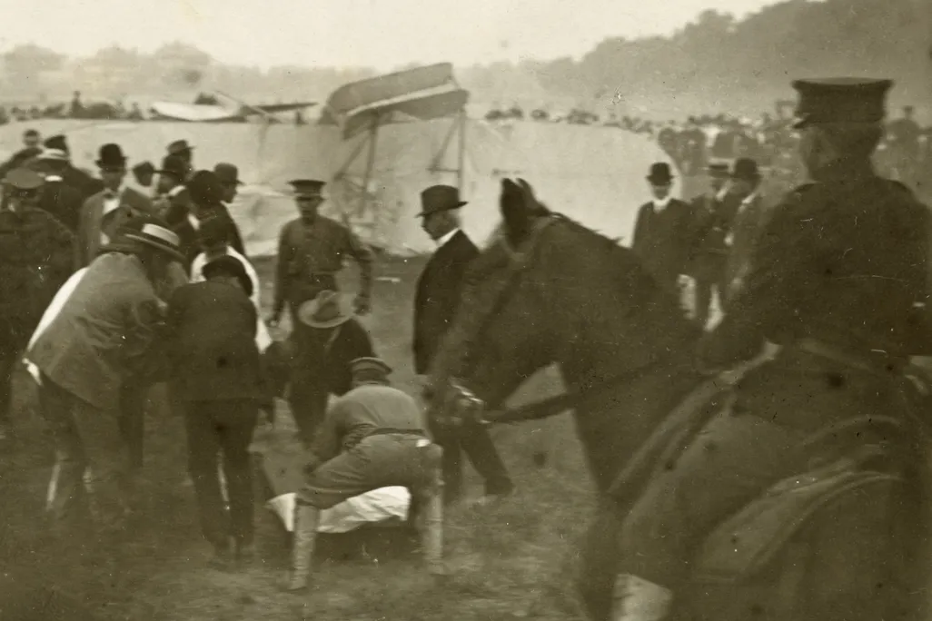 Bystanders crouch over Thomas Selfridge, pulled from the wrecked Wright Model A.