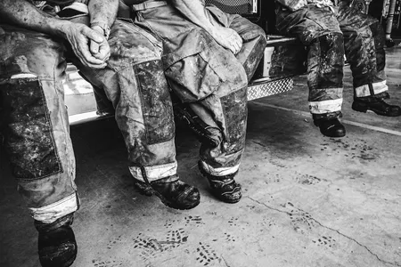 Firefighters, still dressed in their smoke- and soot-stained bunker gear, take a breather after a harrowing day of battling a particularly stubborn brush fire.