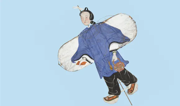 This paper kite depicts a Chinese girl wearing a long-sleeve blue tunic and loose-fitting black plants. A bamboo frame runs the length of the kite behind the paper.