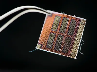 Coated in a conductive polymer material, this half-inch square of fabric contains an array of six rectangular solar cells.