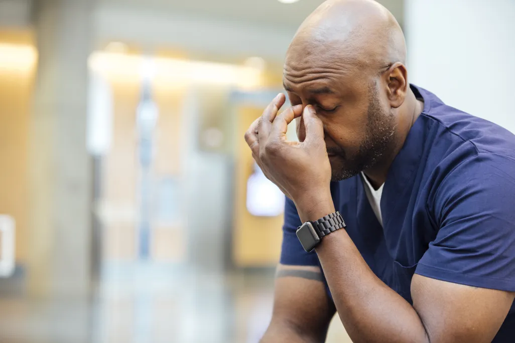 A stressed person pinches the bridge of their nose
