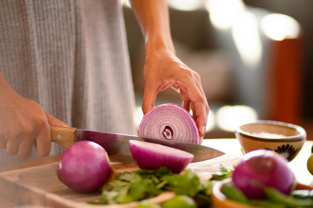 Woman's hands cutting a red onion