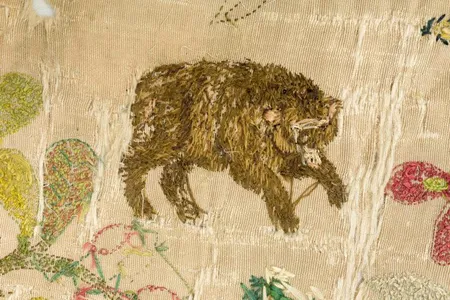 The cloth is embroidered with animals, plants and narrative scenes