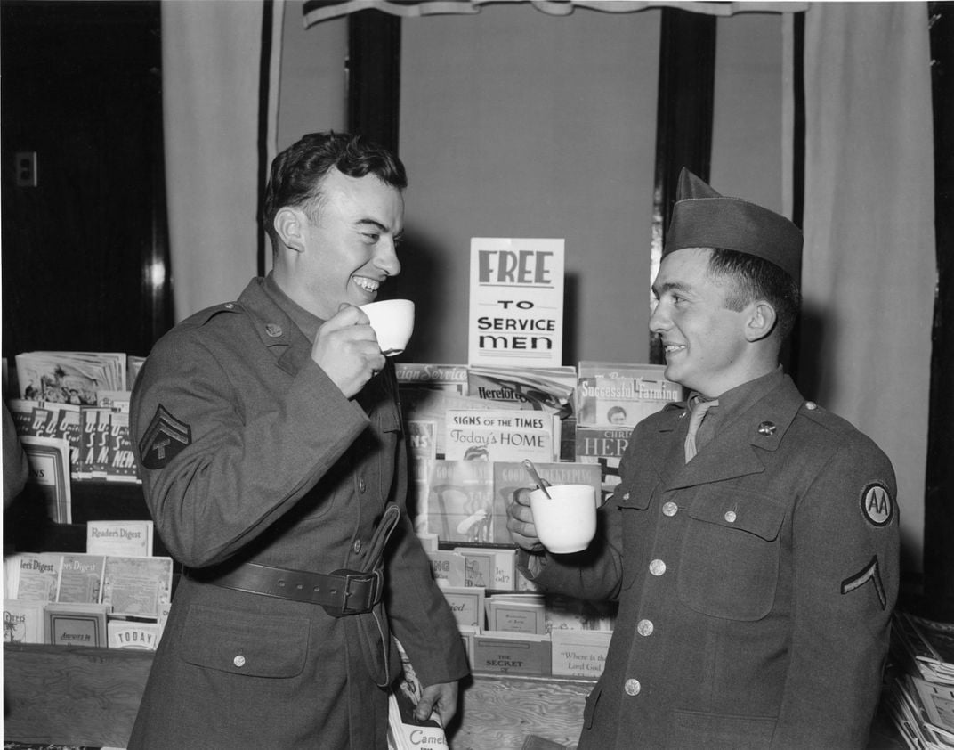 Two soldiers enjoy coffee while grabbing a magazine before hopping back on the train.