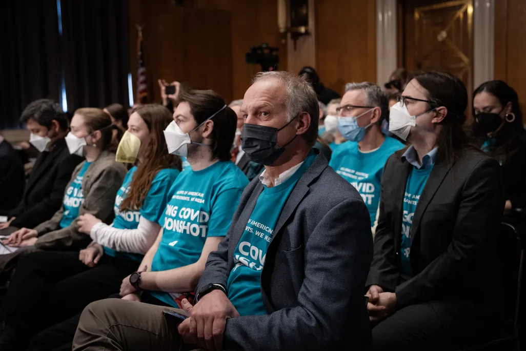 People with masks and blue t-shirts sitting in rows