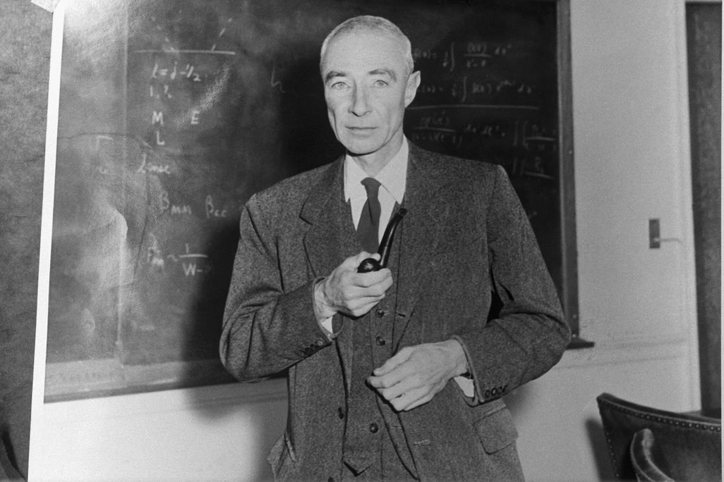J. Robert Oppenheimer in black and white in front of a chalkboard