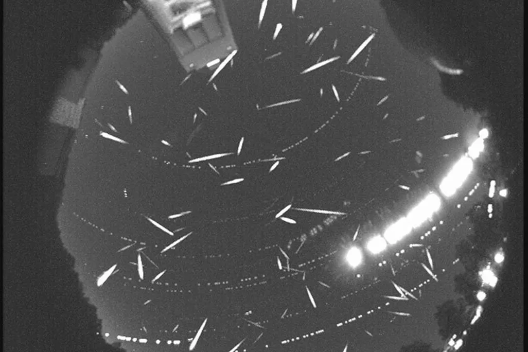 dozens of meteors in the sky in black and white