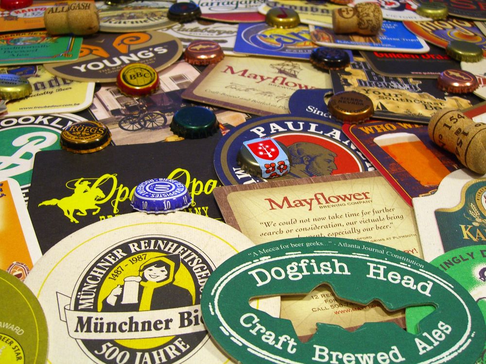 A pile of various beer coasters, wine bottle borks and metal beer bottle caps