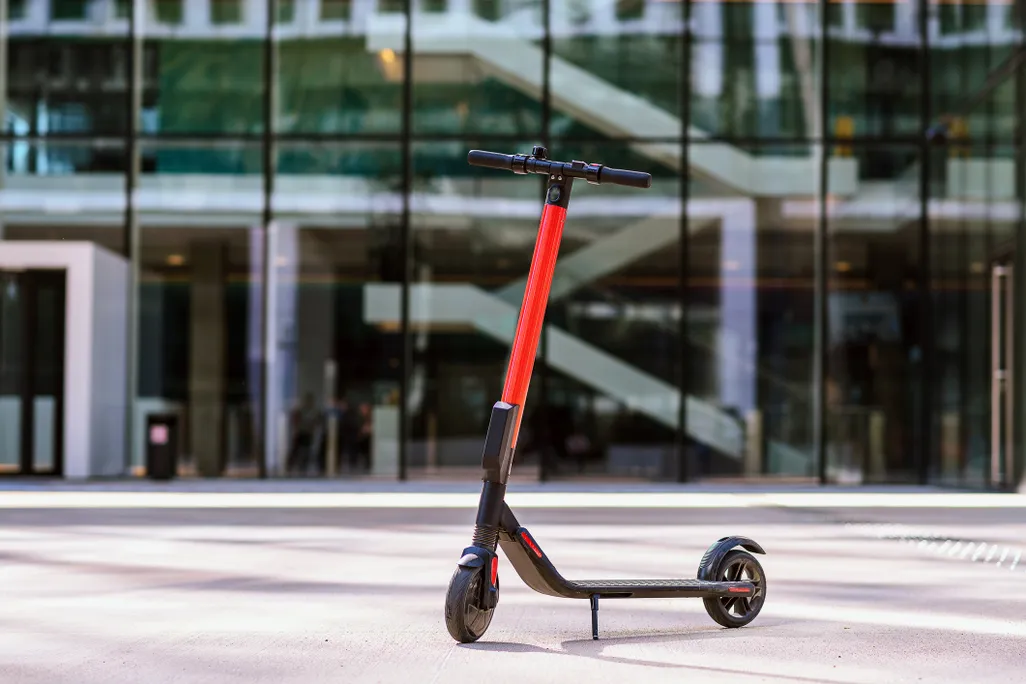 A for-rent electric scooter is photographed in front of a city building