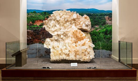 Museum display of the Berns Quartz from the front. The specimen is behind counter-height glass with a backdrop of Arkansas' Ouachita Mountains.